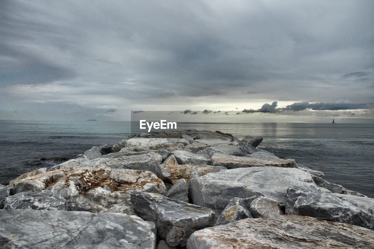 View of rocky beach against cloudy sky