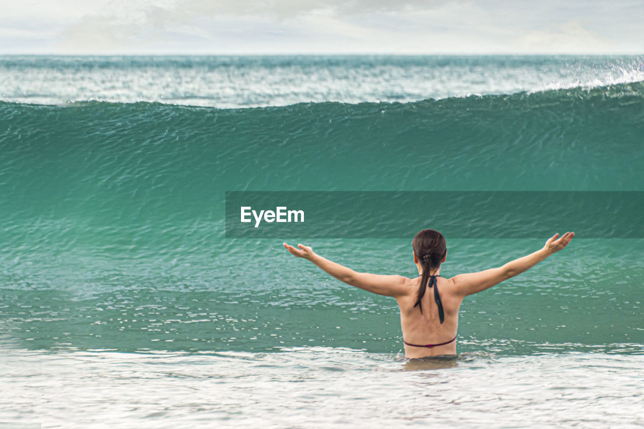 rear view of shirtless man swimming in sea