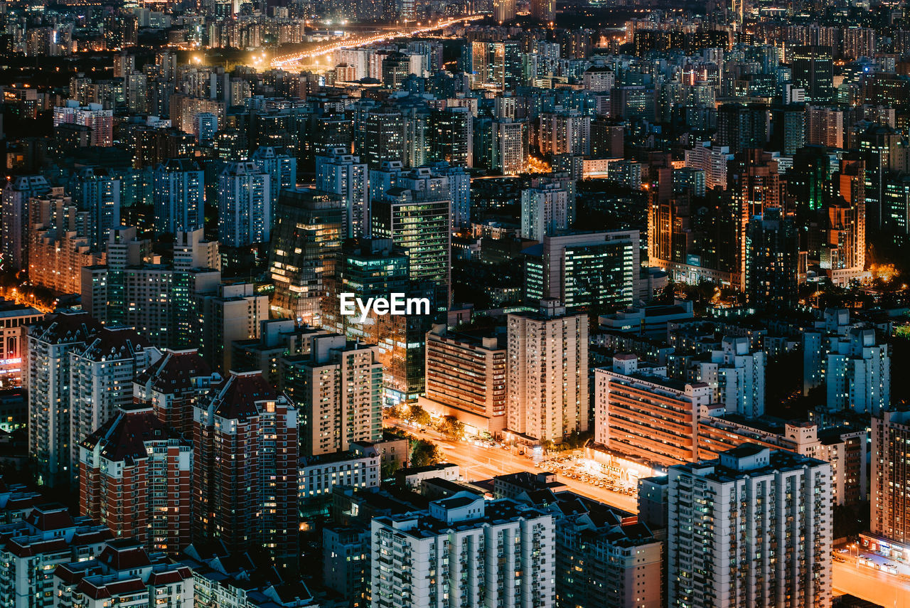 HIGH ANGLE VIEW OF ILLUMINATED CITY BUILDINGS AT NIGHT