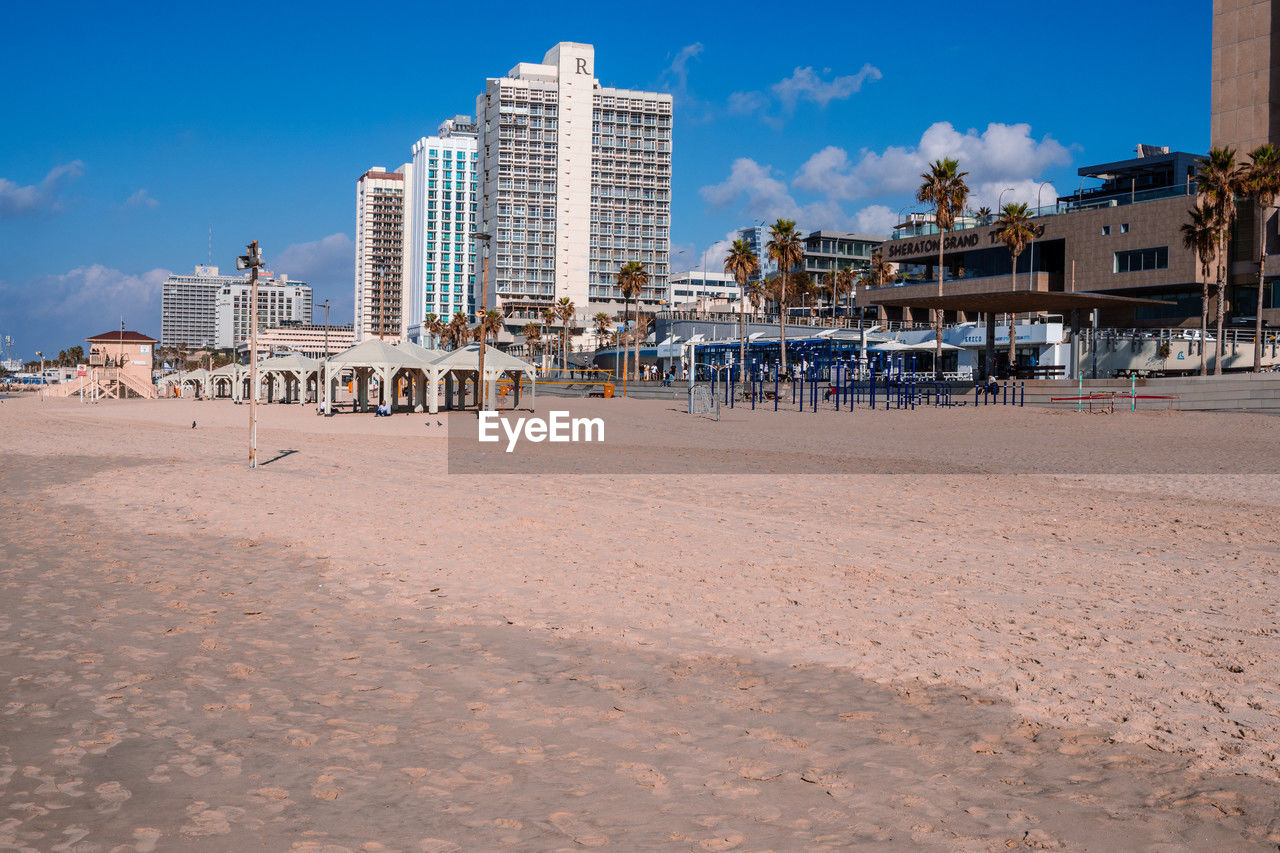 beach, architecture, land, sky, built structure, building exterior, sand, city, building, walkway, nature, vacation, water, travel destinations, boardwalk, sea, coast, landscape, horizon, blue, travel, body of water, shore, trip, holiday, cloud, urban skyline, tourism, residential district, office building exterior, outdoors, cityscape, day, summer, no people, ocean, skyscraper, coastline, sunny