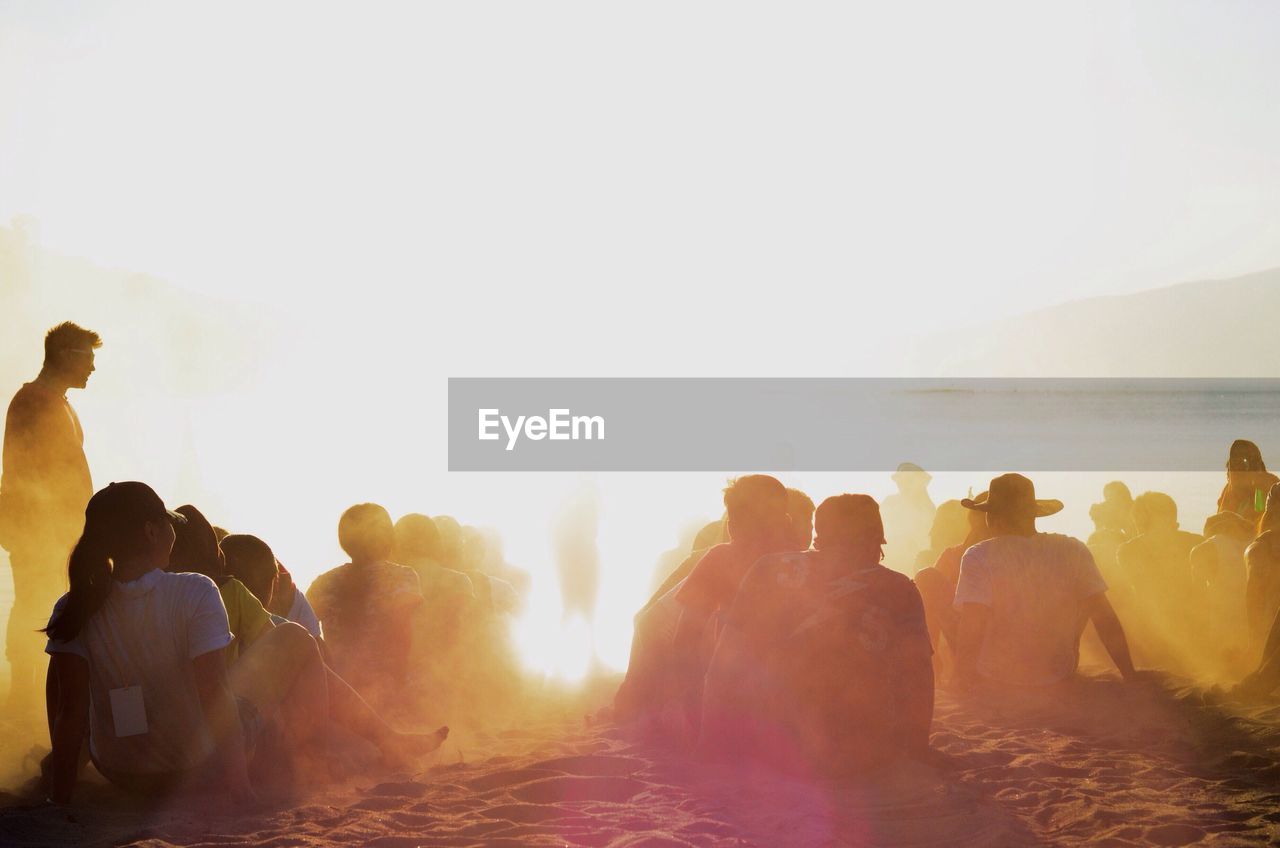 Rear view of group of people sitting on beach