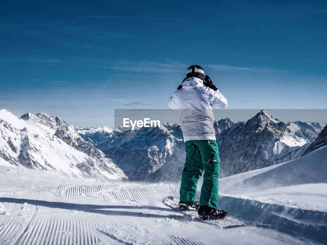 MAN STANDING ON SNOWCAPPED MOUNTAINS AGAINST SKY