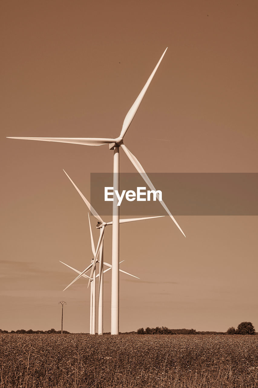 LOW ANGLE VIEW OF WIND TURBINES ON FIELD AGAINST SKY