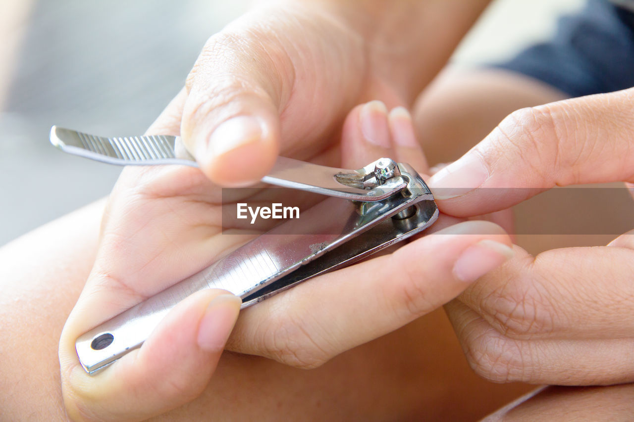 Close-up of woman cutting nails with clipper