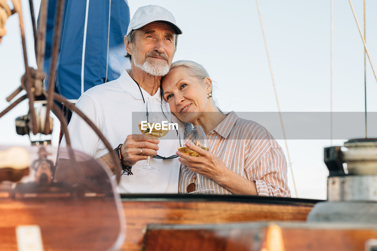 Senior couple holding wineglass standing on boat