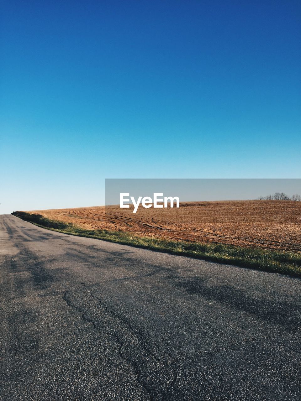 Country road against clear blue sky