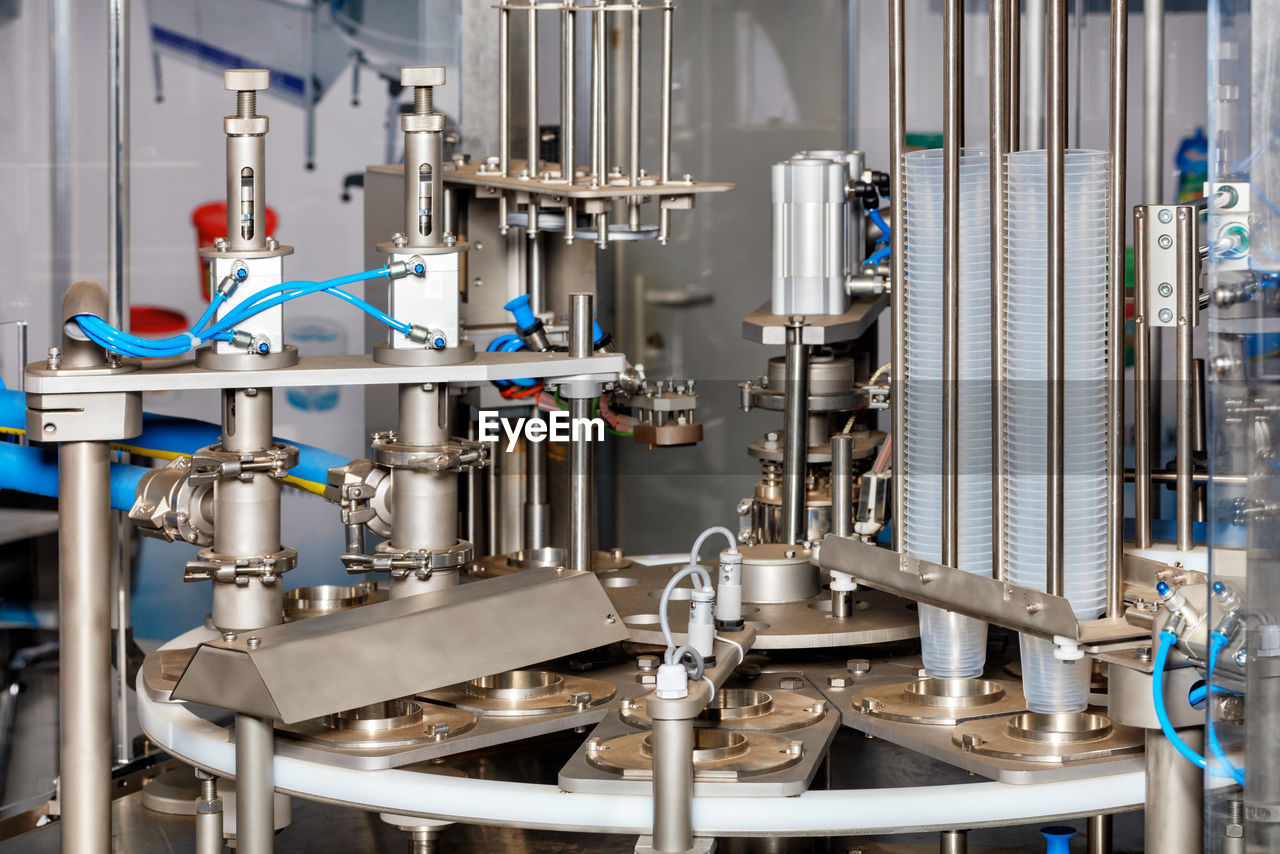 Fragment of food processing production line for filling and packaging dairy products in plastic cups