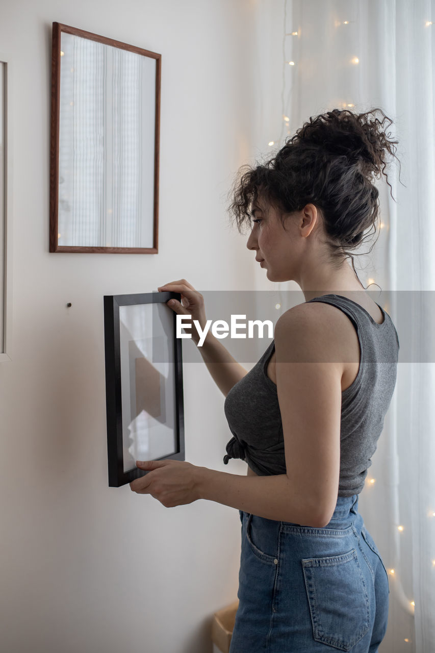 Woman looking at camera while standing against wall