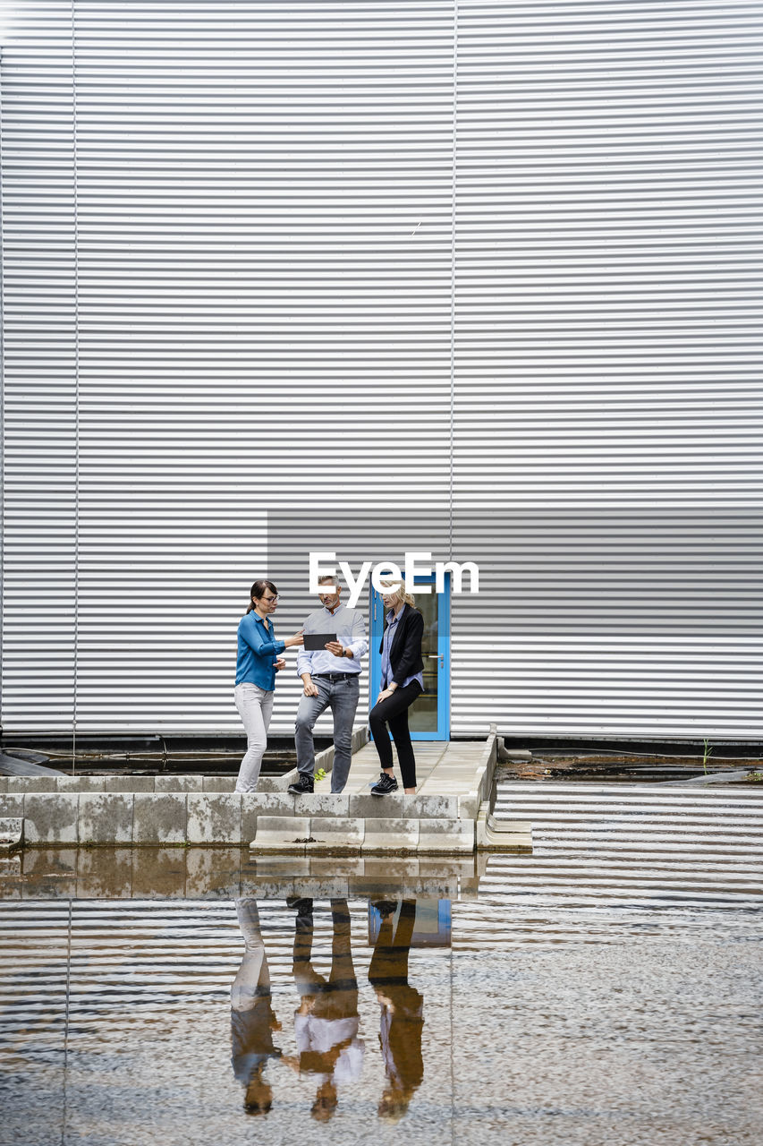 Coworkers using tablet pc in front of industrial building