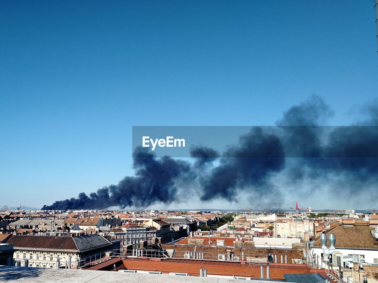 A burning building in town against clear blue sky