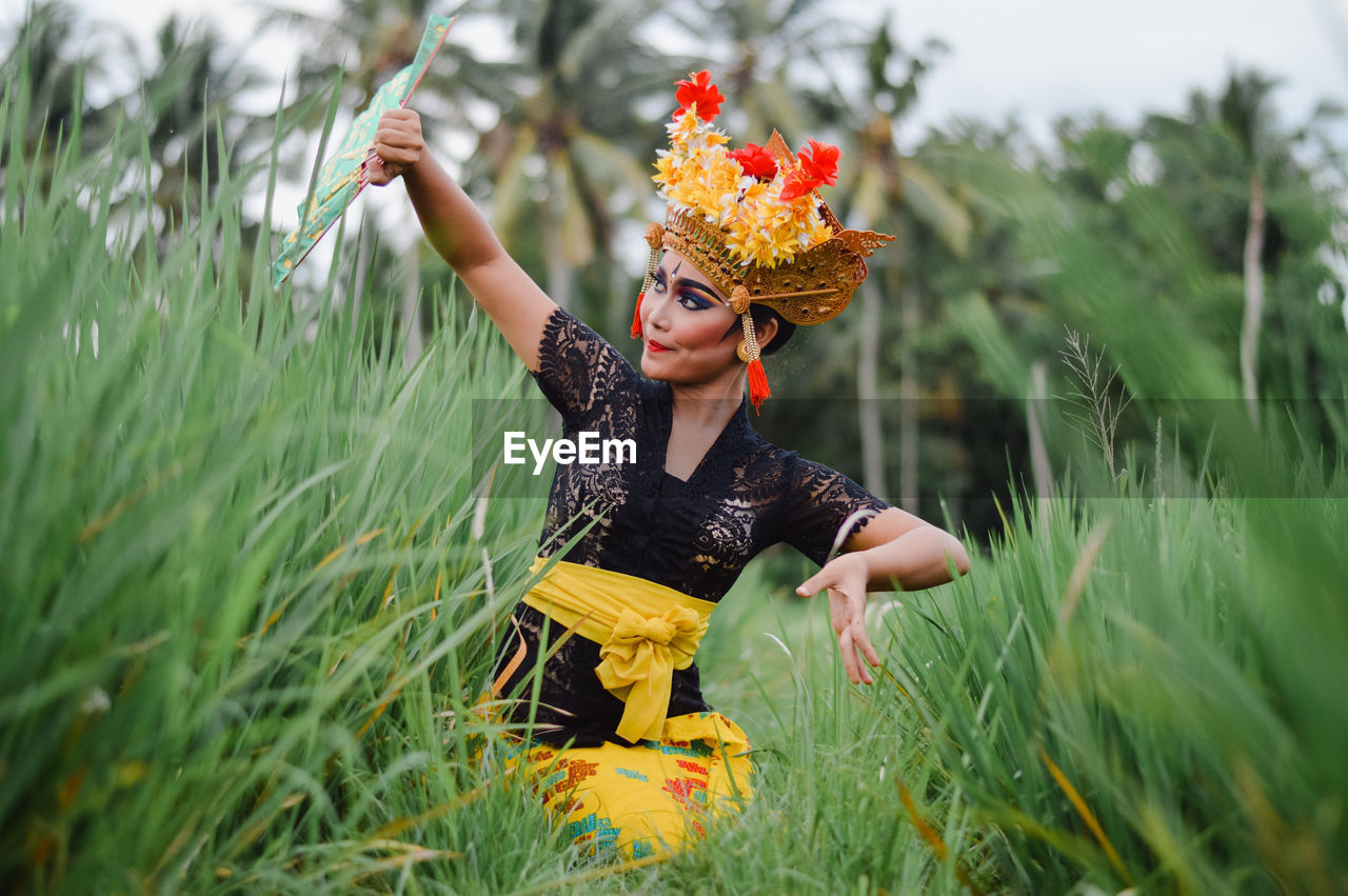 Woman in traditional clothing dancing on grass against sky