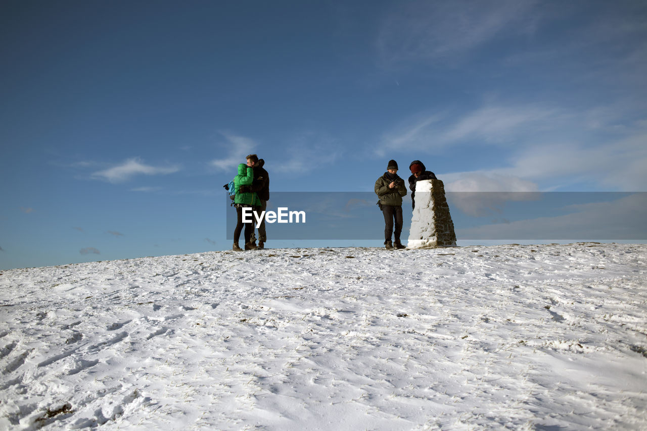 REAR VIEW OF PEOPLE WALKING ON SNOW COVERED LAND