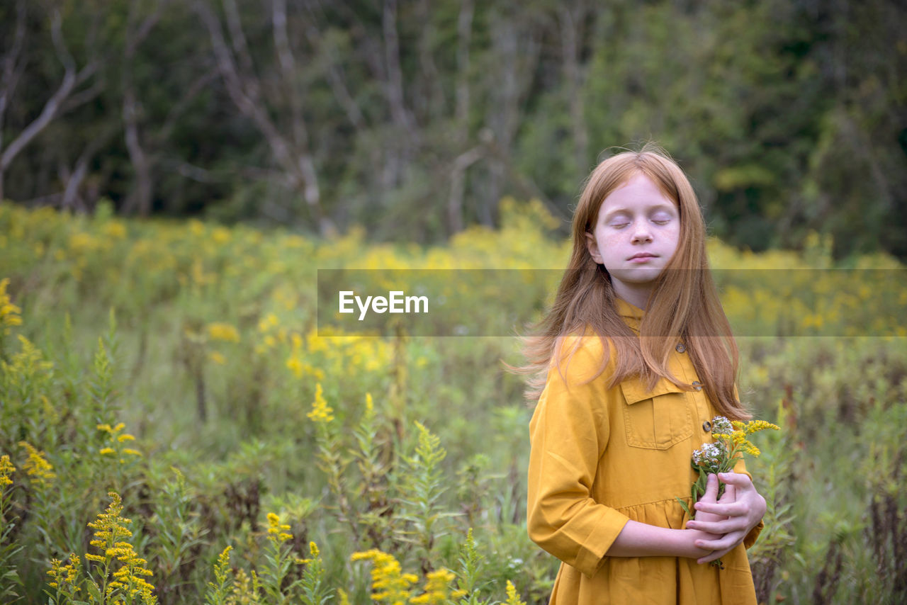 Young girl in yellow dress in a field of flowers