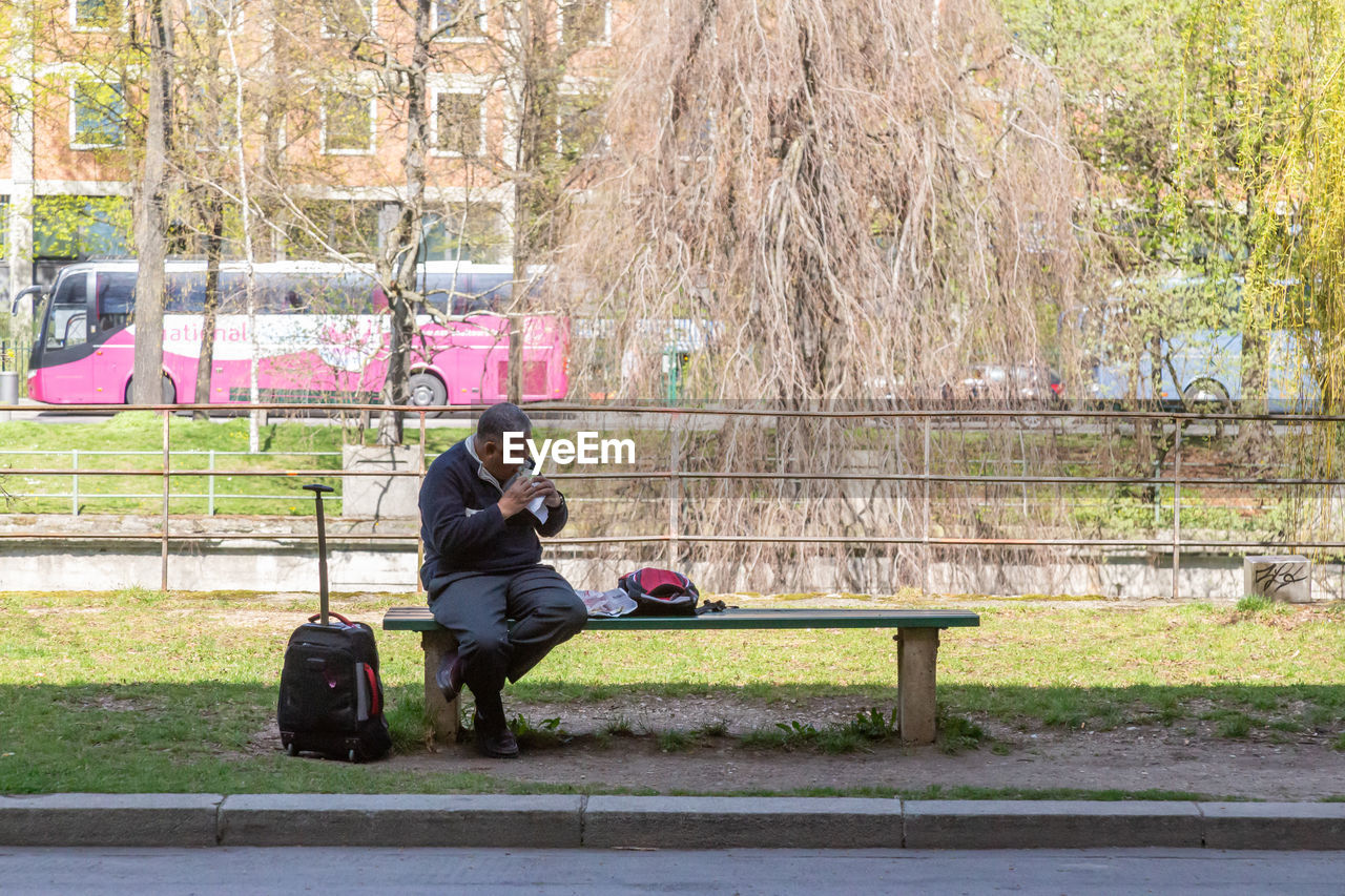 WOMAN SITTING ON BENCH AT PARK