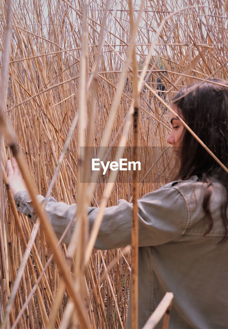 WOMAN STANDING BY PLANTS