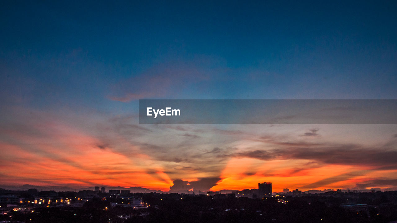 Silhouette cityscape against sky at night