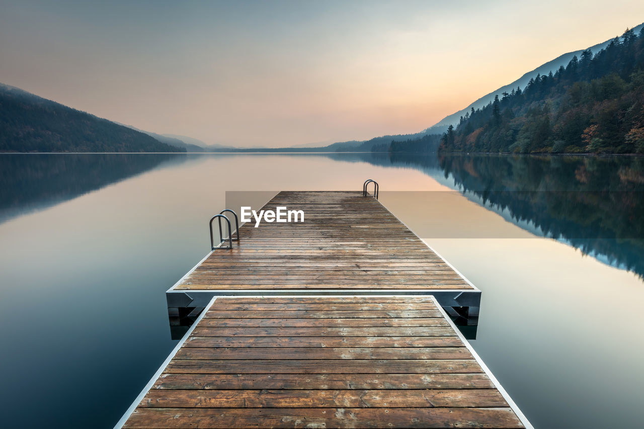 A swimming platform extending onto a calm cultus lake on a smoky autumn morning