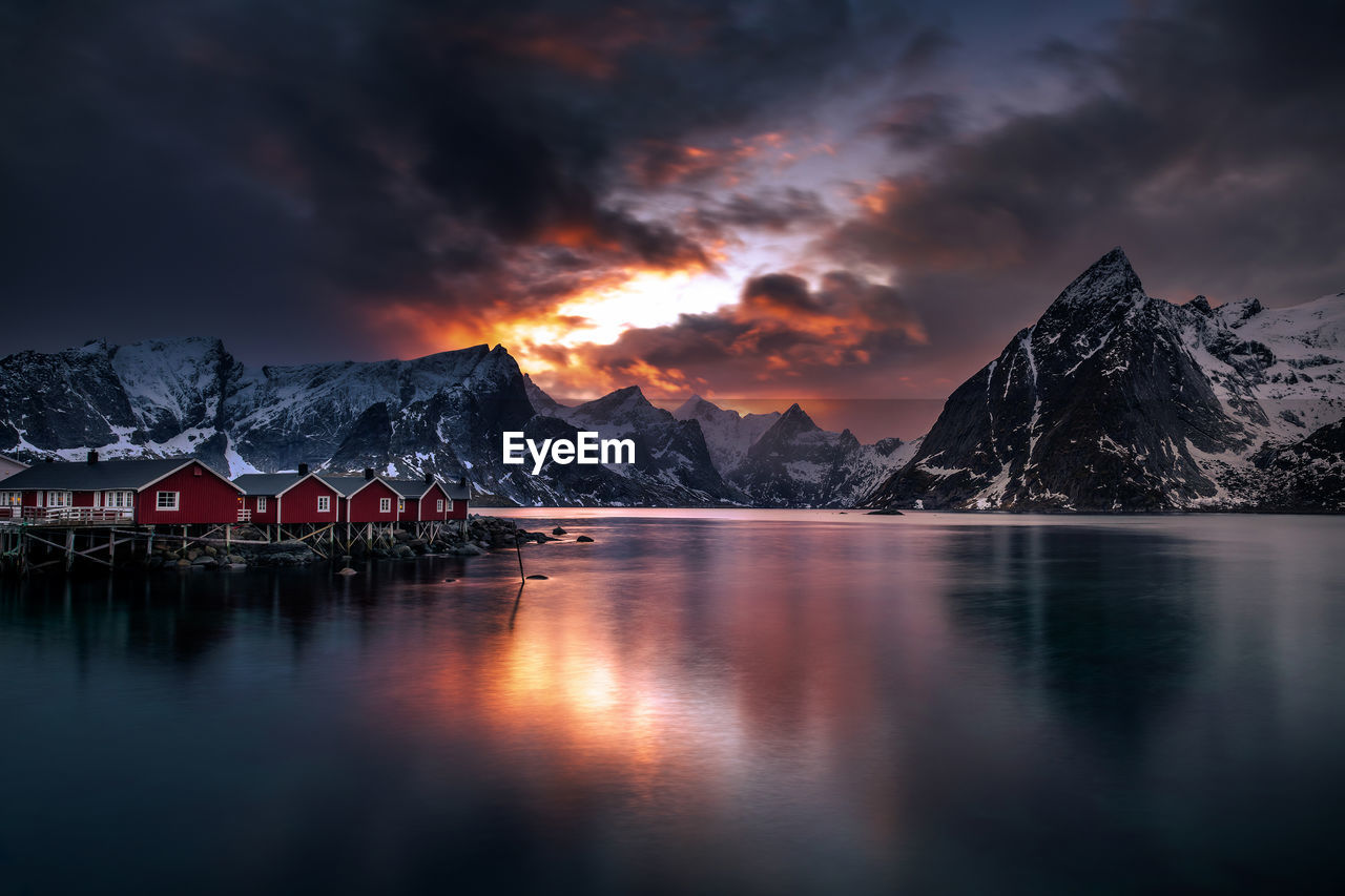 SCENIC VIEW OF LAKE BY MOUNTAIN AGAINST SKY DURING SUNSET