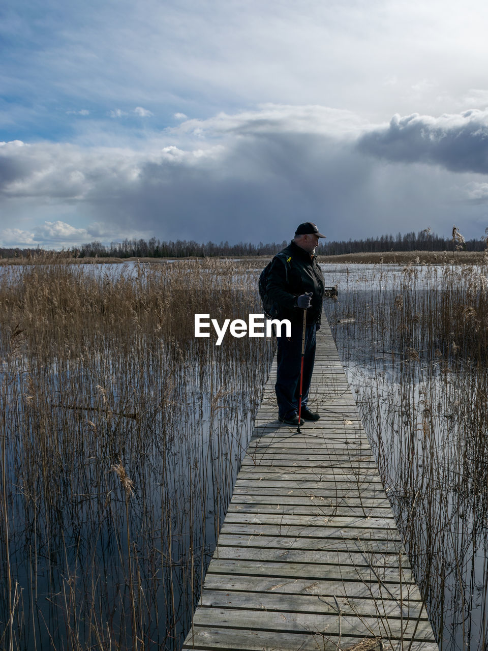 FULL LENGTH OF MAN STANDING ON PIER AT LAKE