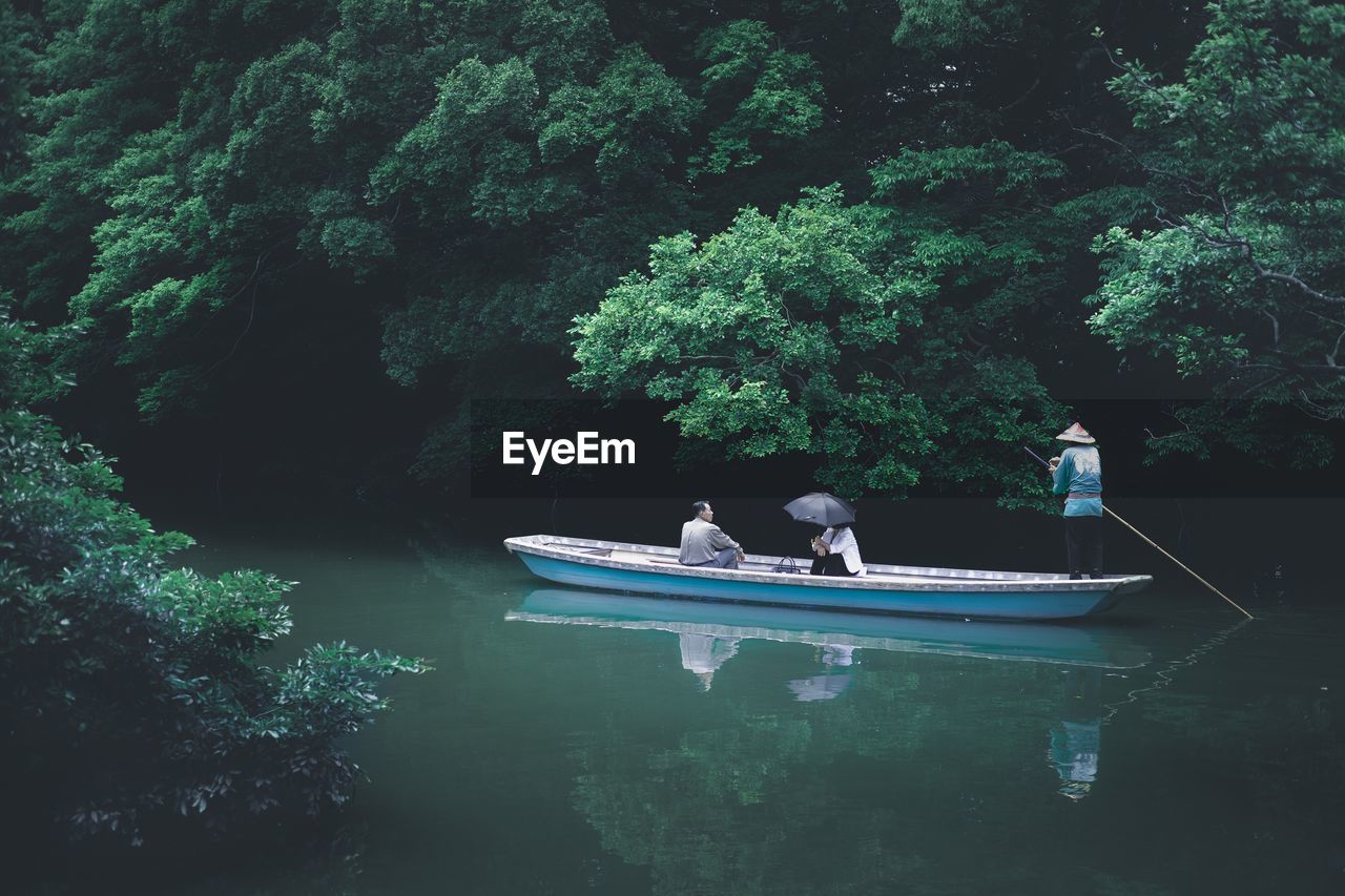 PEOPLE IN BOAT SAILING ON LAKE