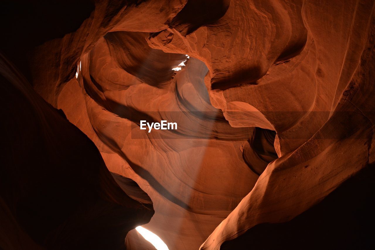 Low angle view of sunbeam streaming from rock formation in antelope canyon