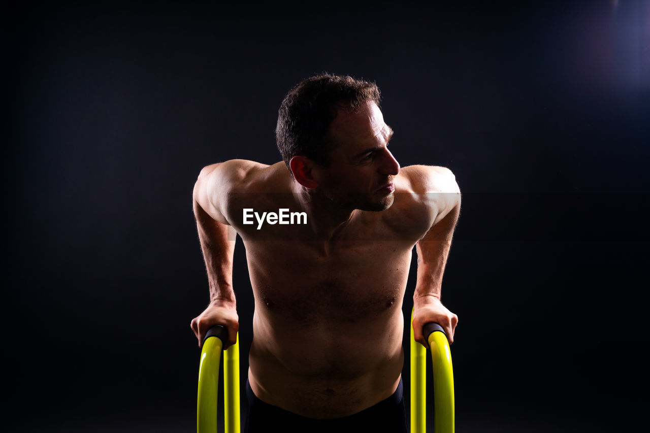 side view of shirtless man exercising in gym