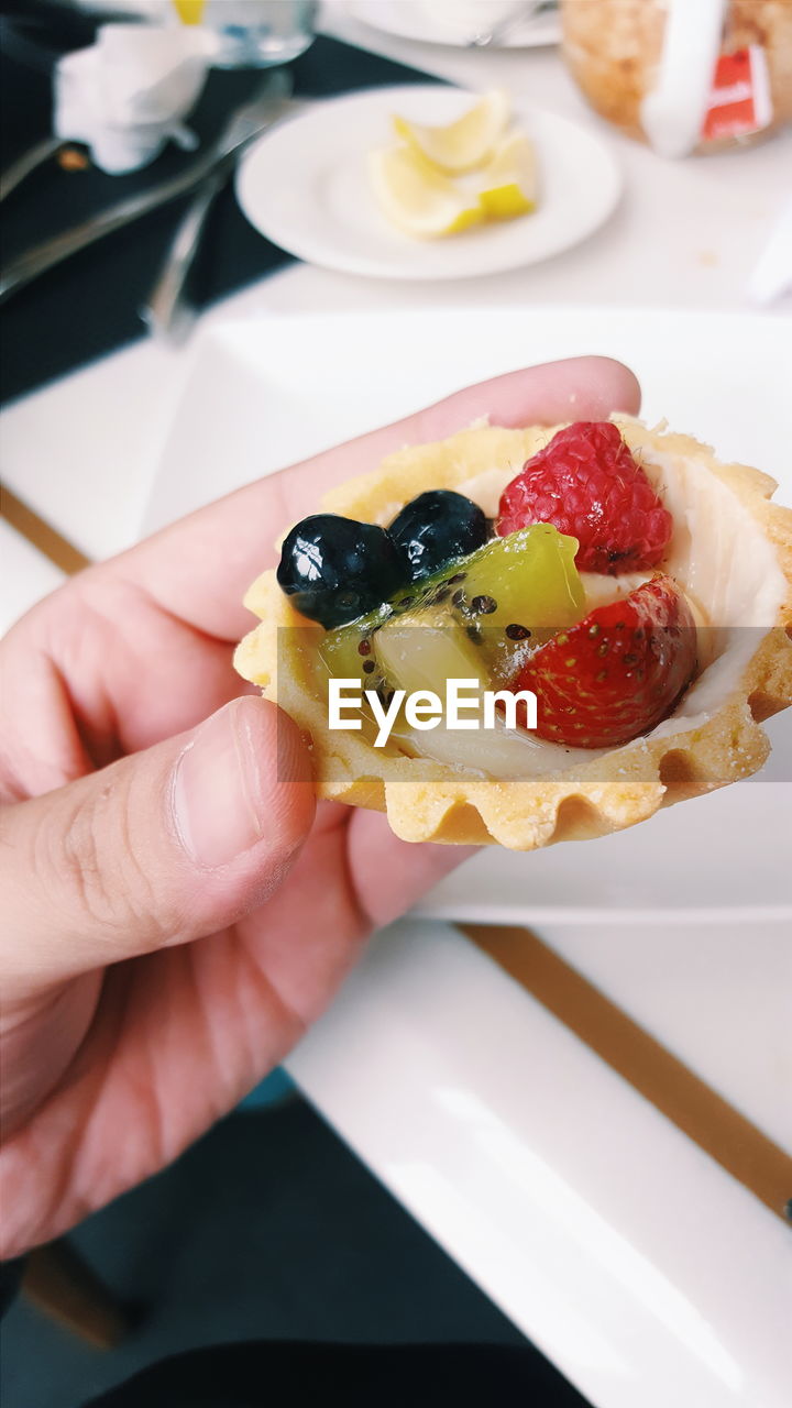 Cropped image of hand holding dessert at table