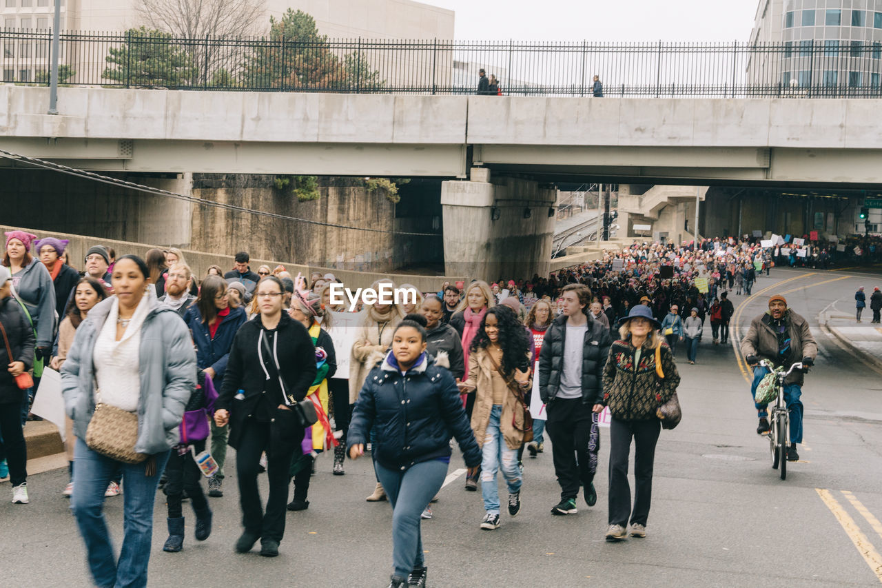 GROUP OF PEOPLE WALKING ON BRIDGE