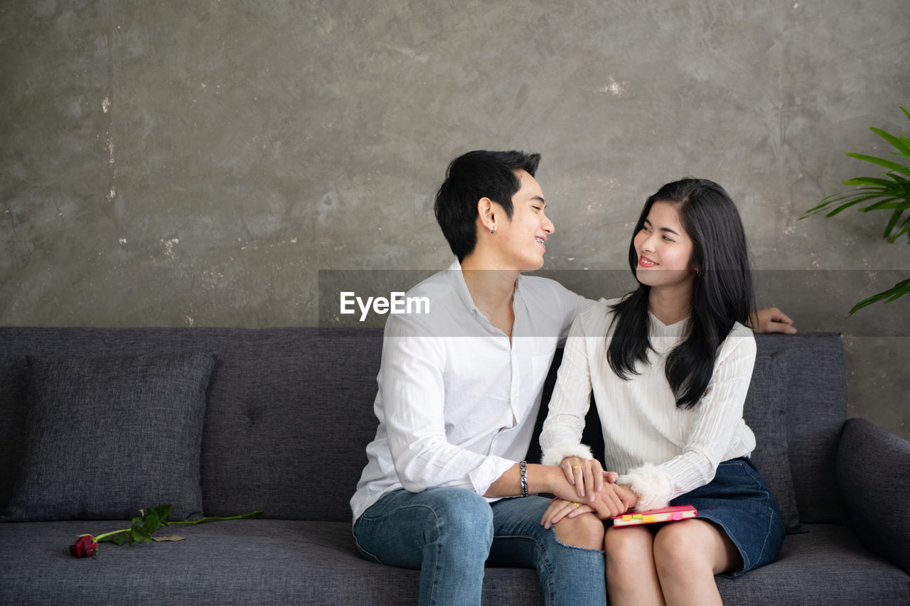 Smiling young couple sitting on sofa at home