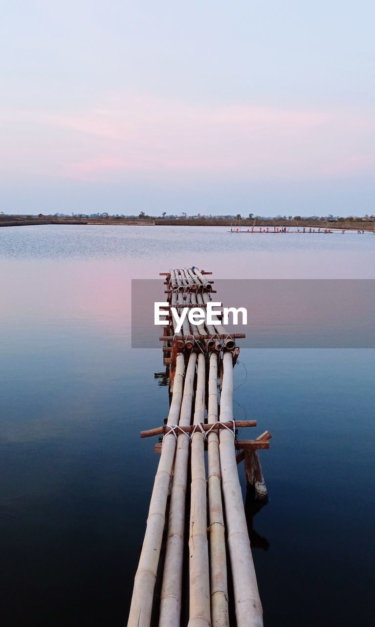 WOODEN POSTS IN LAKE AGAINST SKY