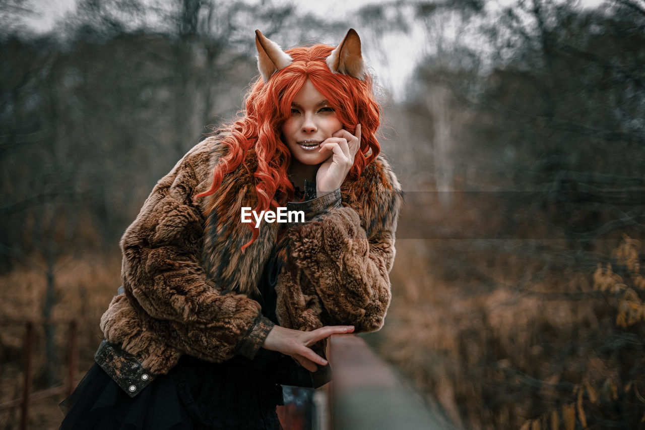 Portrait of woman with dyed hair standing in forest during autumn