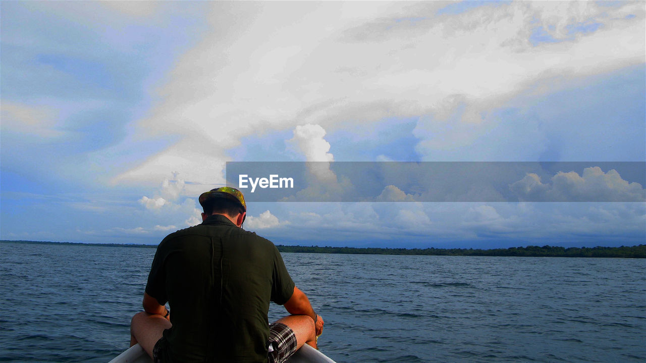 REAR VIEW OF WOMAN STANDING BY SEA AGAINST SKY