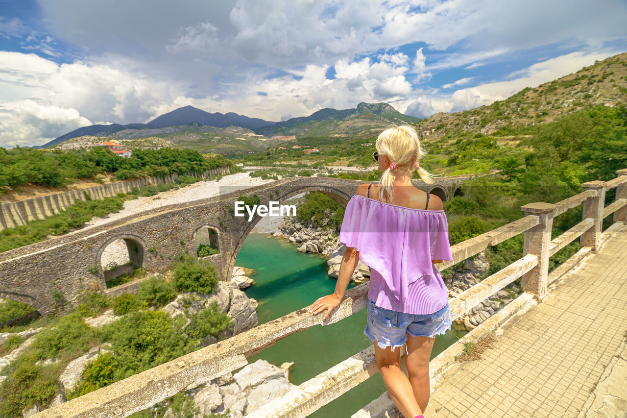 rear view of woman standing on bridge against mountain