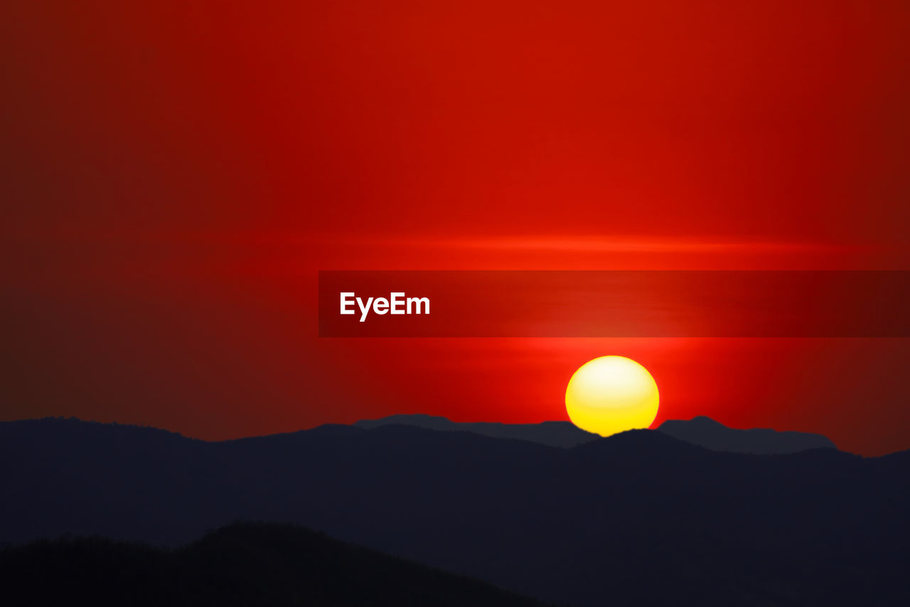 SILHOUETTE MOUNTAIN AGAINST ORANGE SKY