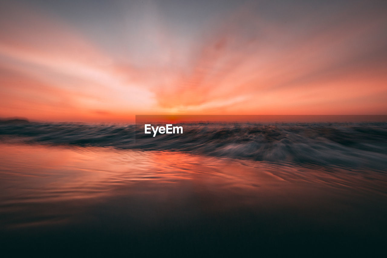 Long exposure image of sea against romantic sky at sunset