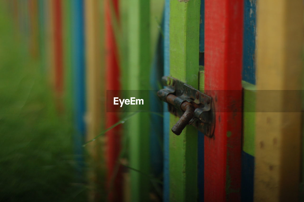 Close-up of latch of multi colored fence