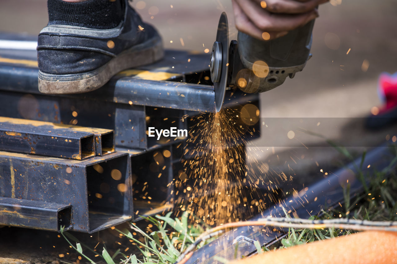 Close-up of worker using angle grinder to cut steel.