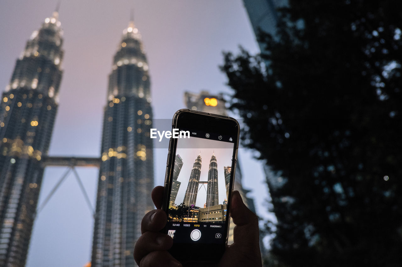 LOW ANGLE VIEW OF PERSON PHOTOGRAPHING TOWER