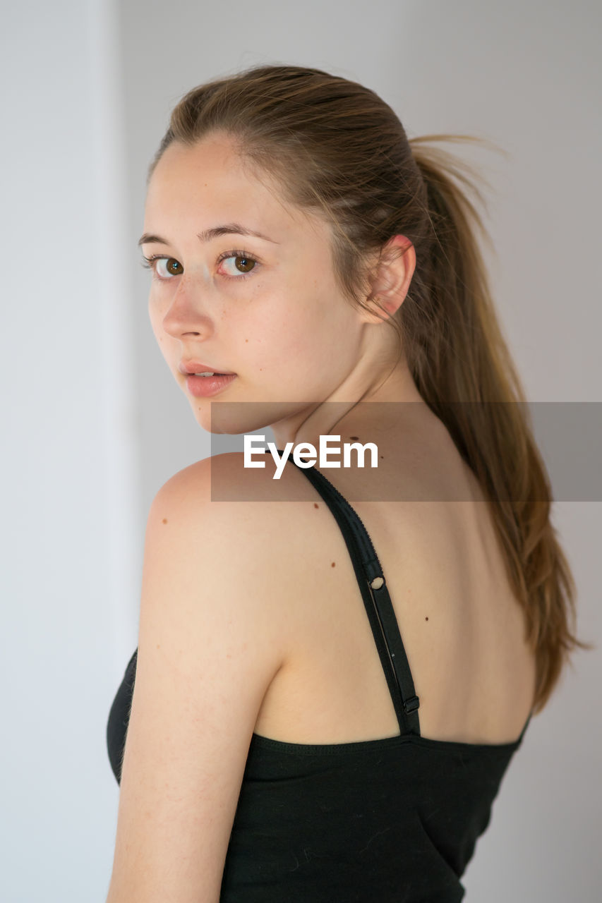 PORTRAIT OF YOUNG WOMAN AGAINST WHITE BACKGROUND