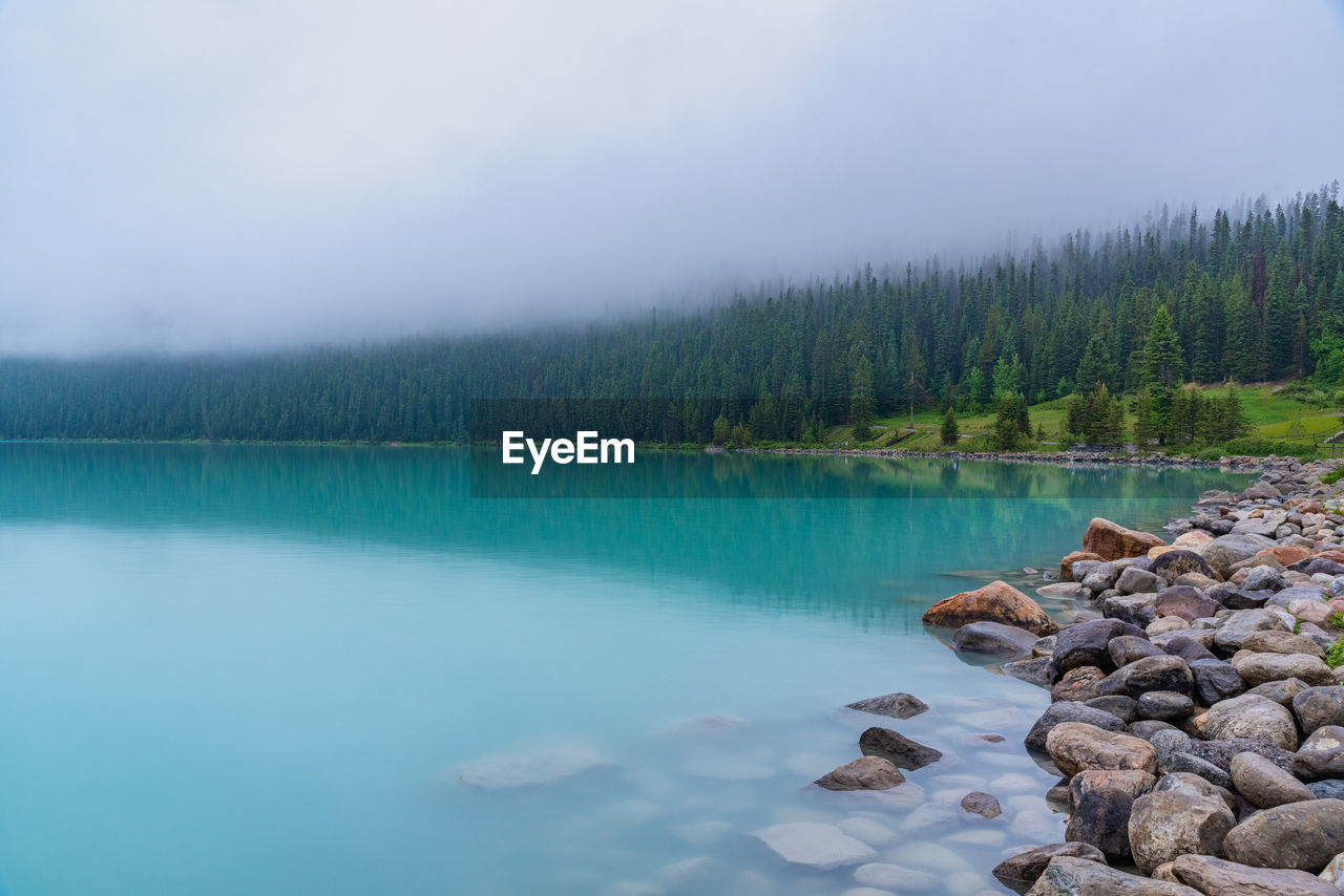 ROCKS BY LAKE AGAINST SKY