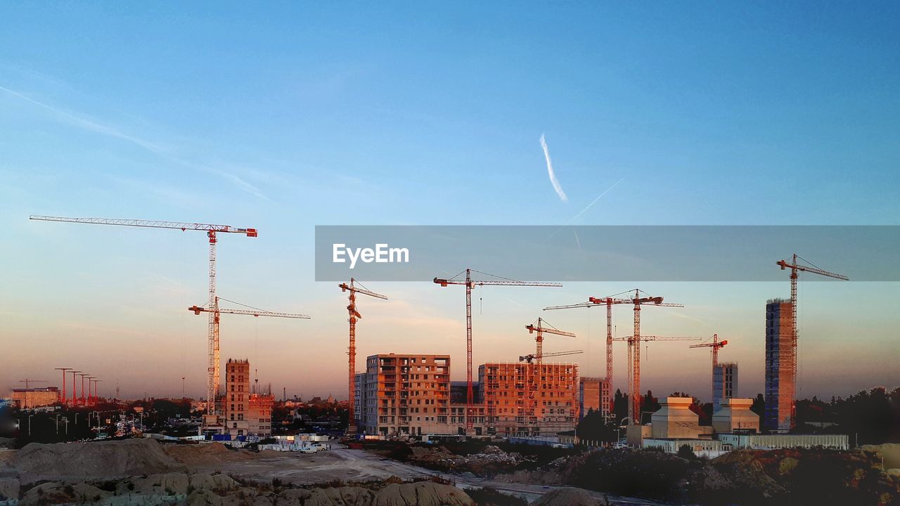 Construction site against sky during sunset