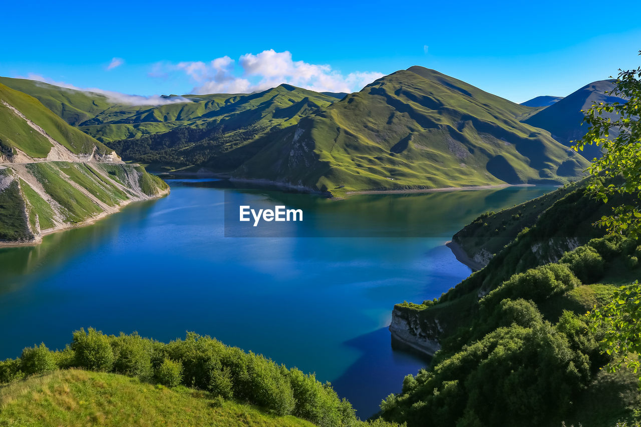 Lake kezenoy am in the green mountains. scenic view of lake and mountains against blue sky