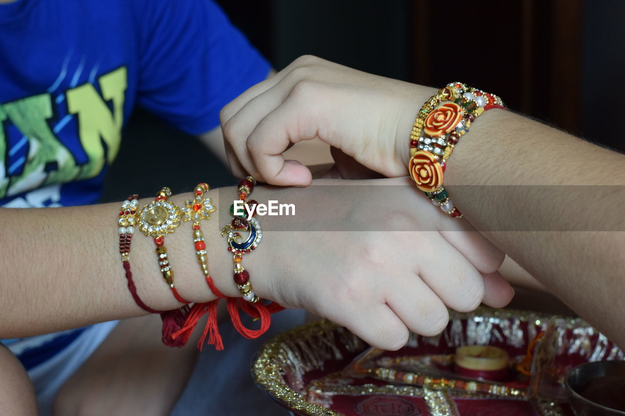 Closeup shot of sister tying rakhi on brother's hand