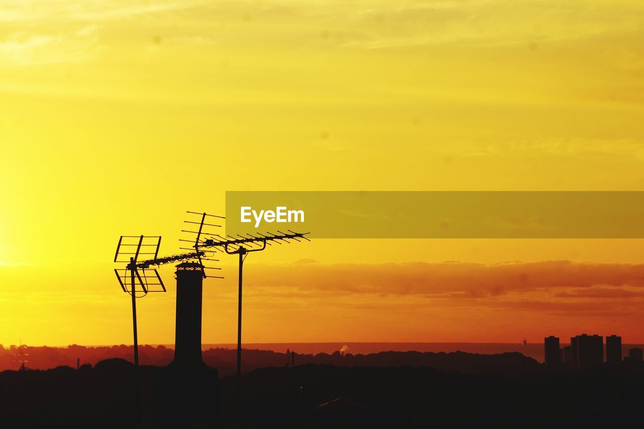 sunset, sky, afterglow, technology, silhouette, horizon, yellow, orange color, dawn, architecture, built structure, nature, electricity, no people, landscape, beauty in nature, cloud, power generation, environment, cable, outdoors, evening, sun, building exterior, scenics - nature, electricity pylon, dramatic sky, industry, sunlight, copy space, power supply, communication, city, building, tower