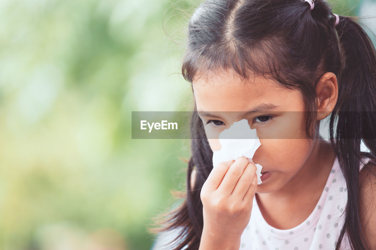 Girl wiping nose with tissue paper