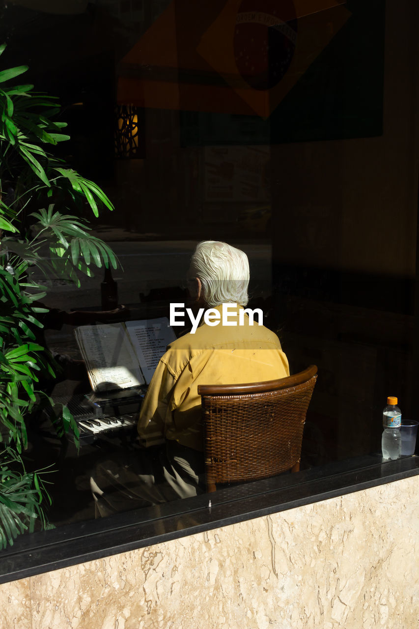 Man wearing yellow shirt and playing piano in restaurant