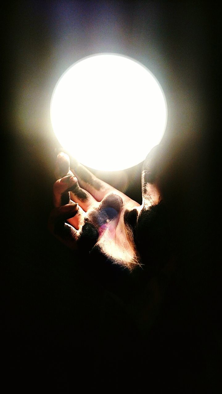 Cropped image of dirty hand touching illuminated light bulb
