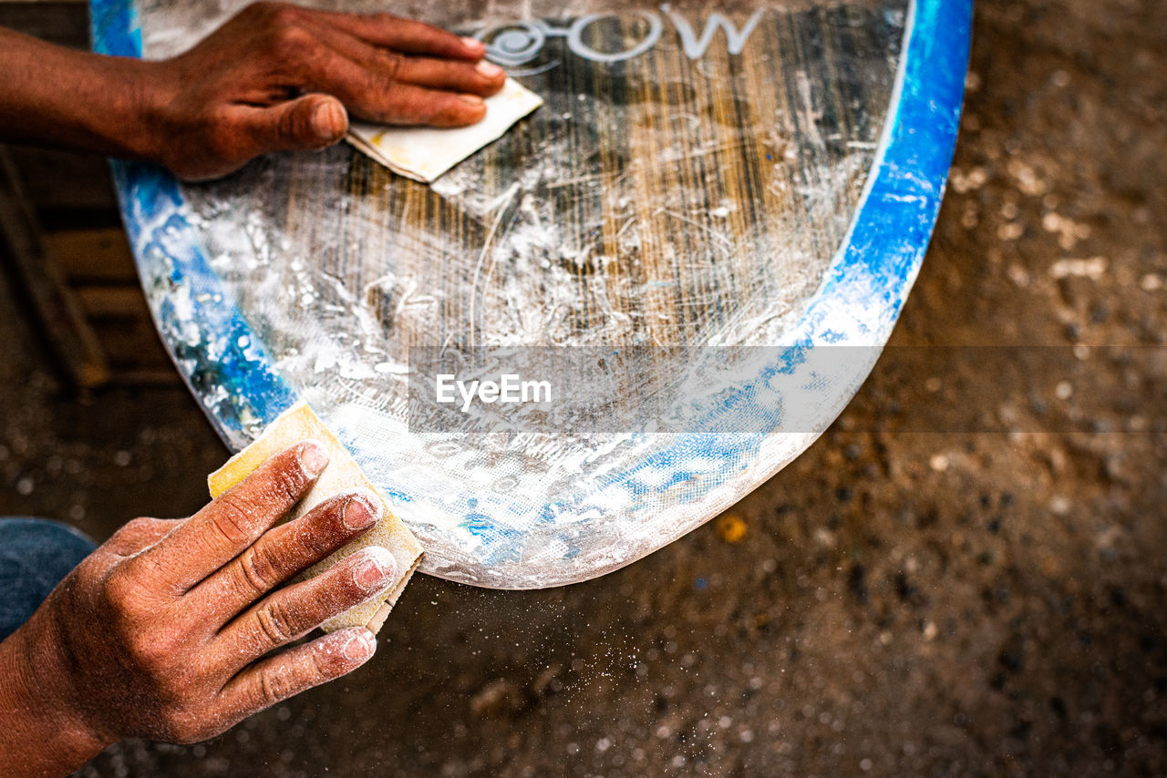 Hands working on surfboard