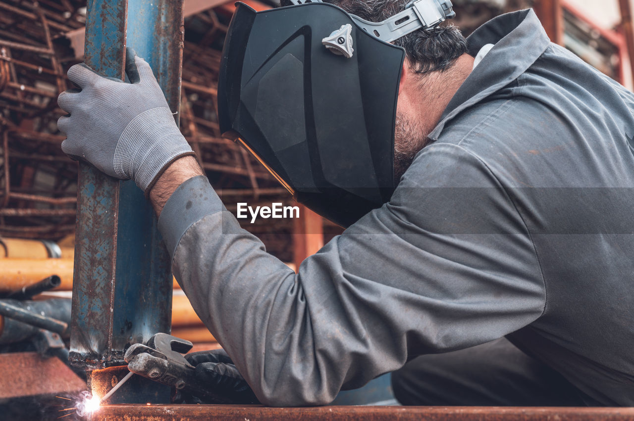 MIDSECTION OF MAN WORKING ON METAL IN KITCHEN