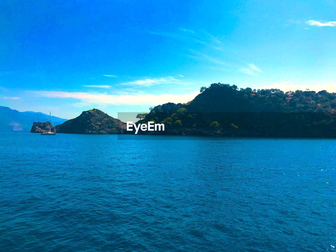 SCENIC VIEW OF SEA AND MOUNTAINS AGAINST BLUE SKY